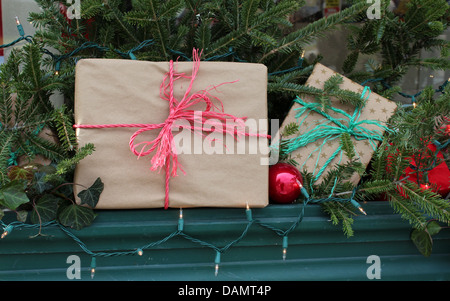 Simple rustic wrapping on many boxes used as decoration in window boxes with colorful twine tied around them and holiday lights. Stock Photo