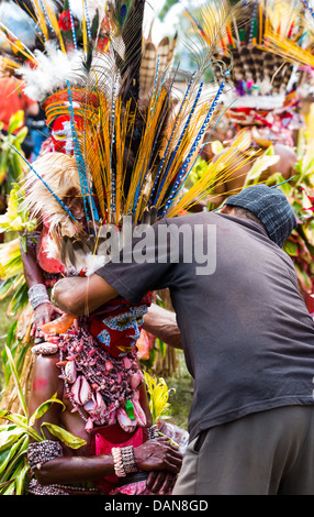 Man adjusting the large ornamental headdress of a dancer at the Goroka show in Papua New Guinea Stock Photo