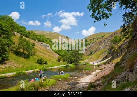 Tourists sat by the River Dove in Dovedale Derbyshire peak district national park England UK GB Europe Stock Photo