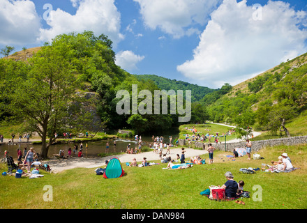 Tourists sat by the River Dove in Dovedale Derbyshire peak district national park England UK GB EU Europe
