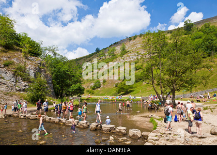 Tourists crossing River Dove on stepping stones in Dovedale Derbyshire peak district national park england UK GB EU Europe Stock Photo