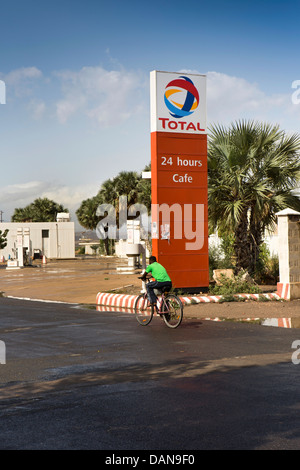 Africa, Eritrea, Massawa, Tualud Island, man cycling past Total Petrol station Stock Photo