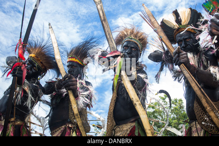 Looking up at a group of tribal warriors with drawn bow and arrows, Papua New Guinea Stock Photo