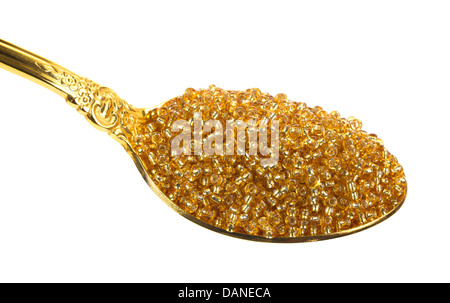 A gold spoon filled with gold glass beads. Stock Photo