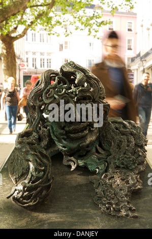 The bronze and granite sculpture “Conversation with Oscar Wilde” made by Maggi Hambling. People are rushing past to Charing Cross Station. London, UK. Stock Photo