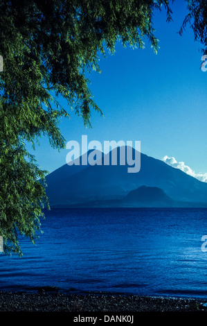 Scenic view of Lake Atitlan with Vocano Toliman and Atitlan and Cerro de Oro framed by a tree on the northern shore of the lake. Stock Photo
