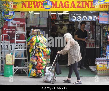 An old woman pushes her cart down 49th street in Manhatten, New York, USA, 13 July 2011. US President Barack Obama wrestles with Congressional leaders over an agreement on the nation's debt. If the issue is not solved until 02 August 2011, it is not guaranteed that an estimated 50 million checks for pensioners, retired military personnel, the disabled and other government beneficia Stock Photo