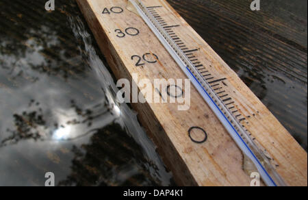 ILLUSTRATION - A thermometer, lying in the rain, shows a temperature of 14 degree Celsius in Buchloe, Germany, 24 July 2011. The weather in south Bavaria is cold and rainy. Photo: KARL-JOSEF HILDENBRAND Stock Photo