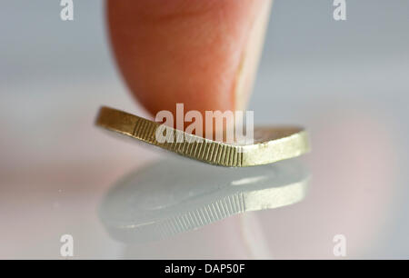 FILE - ILLUSTRATION - An archive picture dated 4 June 2011 shows a bent One-Euro-coin under a thumb in Frankfurt/Main, Germany. Photo: Frank Rumpenhorst Stock Photo