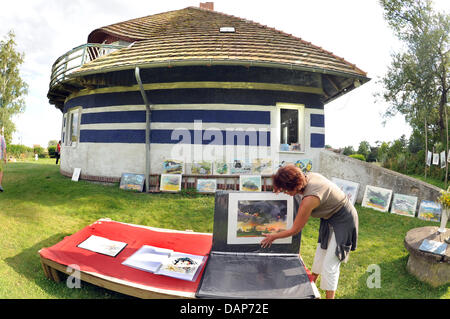A vacationer views artworks, created by the painter Harald Kolb from Rheinsberg during en plein air, in the garden of the former summer house of the Danish silent film diva Asta Nielsen on Hiddensee Island in Vitte, Germany, 19 July 2011. The round house, which was built by the Berlin architect Max Taut in 1922/23, was acquired by the silent film actress in 1928. The house has been Stock Photo