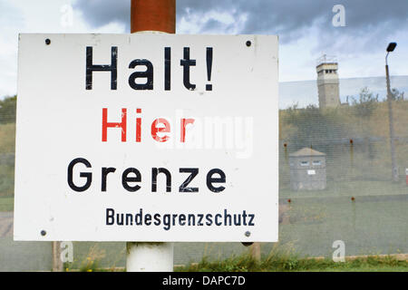 A West German sign with the lettering 'Stop! Border here' is pictured in Schlagdorf in front of the former GDR border fence, Germany, 10 August 2011. The association 'Grenzhus' re-erected the original border installations of the former inner-German border in collaboration with the German federal Border Guard. Photo: Markus Scholz Stock Photo