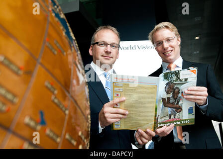 The chairman of the children's aid organisation World Vision Germany, Christoph Waffenschmidt (L) and his representative Christoph Hilligen, hold the annual balance sheet in their hands during the annual press conference in Berlin, germany, 12 August 2011. World Vision Germany calls for a rescue system for the countries at the Horn of Africa and a Task Force to prevent future crise Stock Photo