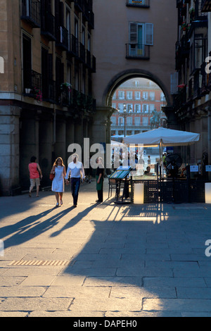 A couple walking out of one of the large entrances to Plaza Major in Madrid, Spain Stock Photo