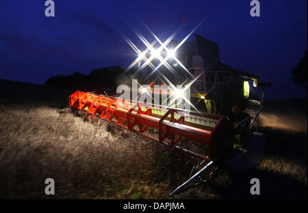 A combine harvester drives through a field after sunset near Gross Welzin, Germany, 22 August 2011. In Northern Germany the rain of the last weeks has destroyed parts of the crops and the harvest often had to be put on hold. According to the Minestry of Agriculture, the farmers' loss could be up to 380 million euro. Photo: Jens Buettner Stock Photo