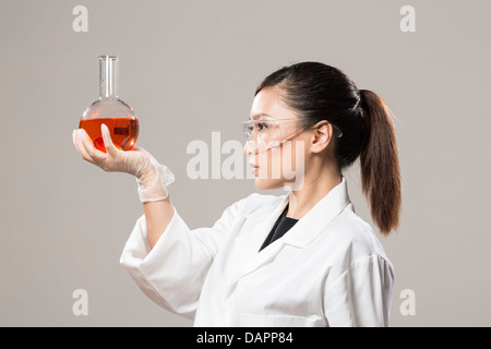 Female Chinese Healthcare professional or scientific researcher looking at a row of test tubes Stock Photo