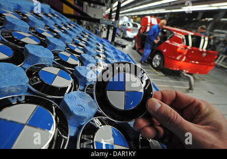 (FILE) An archive photo dated 08 November 2010 shows an employee holding up a BMW emblem in a factory in Regensburg, Germany. BMW continues its record-breaking performance. In August 2011 the car manufacturer from Munich sold 110891 cars and managed to set a new record for the month. Compared to August 2010 deliveries were up 7.4 per cent BMW announced 09 September 2011. Stock Photo