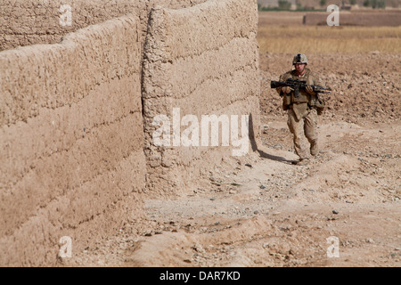 A US Marine runs into an abandoned compound while coming under fire from insurgents during a cordon and search mission June 27, 2013 in Habib Abad, Helmand province, Afghanistan. Stock Photo