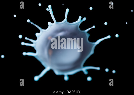 A close-up, high-speed photograph captures a single drop of milk splashing upward, forming a crown-like shape with fine droplets radiating outward. The splash is frozen in motion against a solid Stock Photo