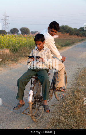 India, Uttar Pradesh, Agra, boy riding on bike rack reading from tablet device Stock Photo