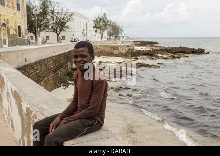 Africa, Mozambique, Mozambique Island. Teenage boy sitting by the sea. Stock Photo