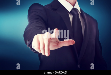 Business man with pointing to something or touching a touch screen on blue background Stock Photo