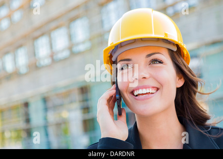 Young Professional Female Contractor Wearing Hard Hat at Contruction Site Using Cell Phone. Stock Photo