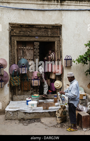 Africa, Tanzania, Zanzibar, Stone Town. Man sitting at roadside shop. Stock Photo