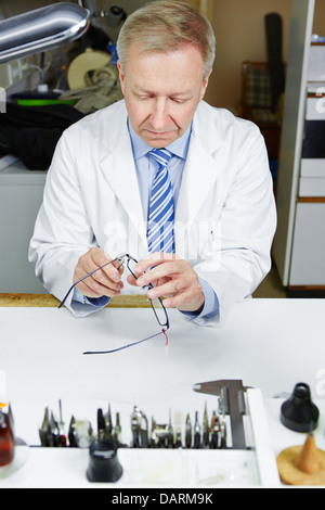 Optician in workshop fixing glasses with pliers Stock Photo