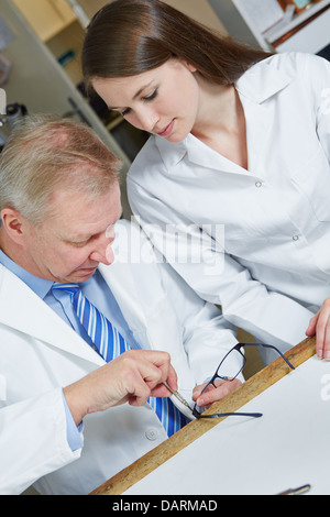 Optician with trainee fixing glasses in workshop Stock Photo
