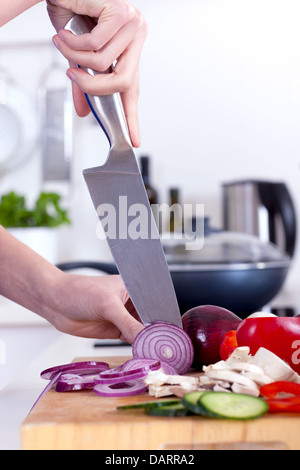 female hands chopping vegetables on a wooden board in the kitchen Stock Photo