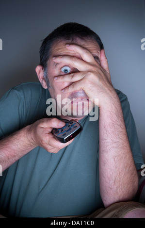man covering face watching tv or television afraid or frightened Stock Photo