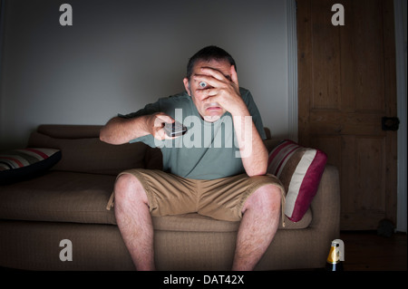 man covering his eyes watching tv or television Stock Photo