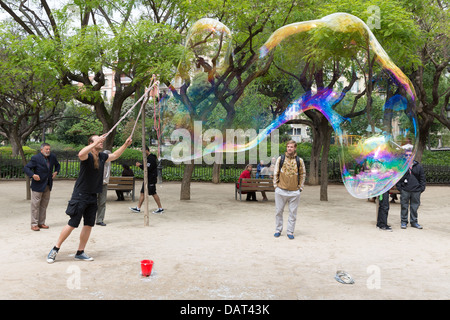 BARCELONA - MAY 16: Unknown street artist makes big soap bubbles in a public park on May 16, 2013 in Barcelona, Spain Stock Photo