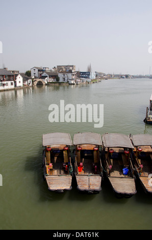 China, outskirts of Shanghai. Zhujiajiao. View of village with traditional wooden boats and ancient stone bridge in distance. Stock Photo