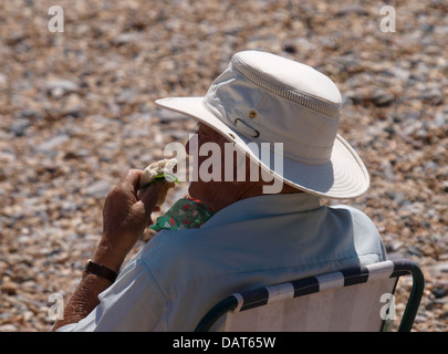 Old man eating sandwich at the beach, Devon, UK 2013 Stock Photo