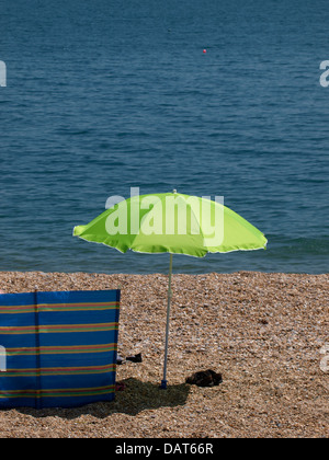 Green sun umbrella and wind break at the seaside, Devon, UK 2013 Stock Photo