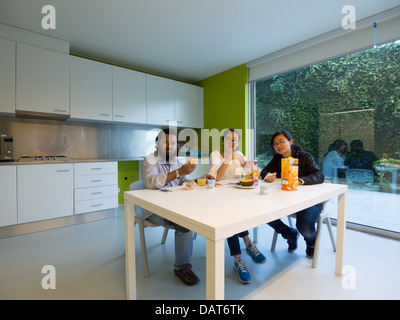 Friends eating breakfast in modern kitchen Stock Photo