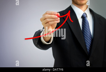 Businessman drawing a red rising arrow over gray background Stock Photo