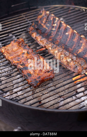 Marinated pork and beef ribs cooking on a domestic barbecue Stock Photo