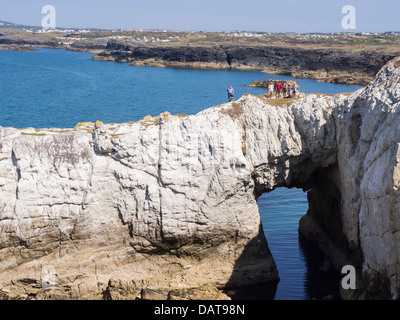 Group of Ramblers on Bwa Gwyn or White Arch natural quartzite rock formation on Isle of Anglesey Coastal Path Rhoscolyn Anglesey Wales UK Britain Stock Photo