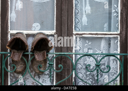 A pair of old leather boots hanging from a front window to dry Stock Photo