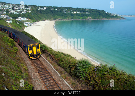 A passenger train passes the beach at carbis bay near st.ives in cornwall, uk Stock Photo