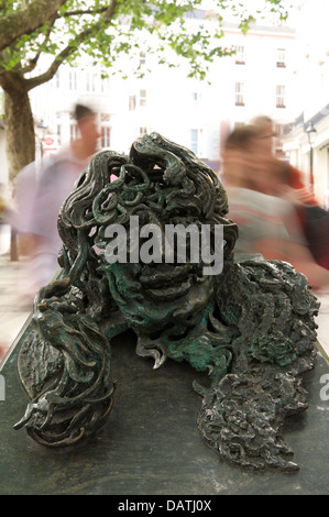 The bronze and granite sculpture “Conversation with Oscar Wilde” made by Maggi Hambling. People are rushing past to Charing Cross Station. London, UK. Stock Photo