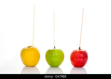 red, yellow and green apples with straws on white background Stock Photo