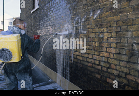 Council contractor removing graffiti from a wall in Greenwich, London, England, UK Stock Photo
