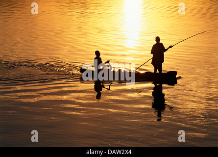 Two local fishermen in a dugout boat on the Luangwa River at sunset, Luambe Nature Reserve, Zambia Stock Photo