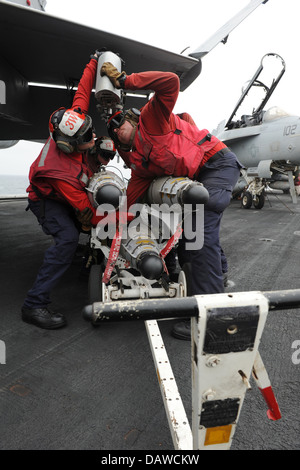 A US Navy Aviation ordnancemen offload a missile from a F/A-18C Hornet fighter aircraft following a mission on the flight deck of the aircraft carrier USS Nimitz July 15, 2013 in the Gulf of Oman. Stock Photo