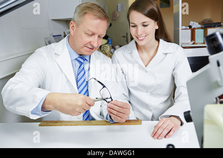 Optician teaching apprentice in workshop how to fix glasses Stock Photo