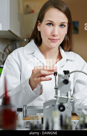 Female optician in workshop using drilling machine for rimless glasses Stock Photo