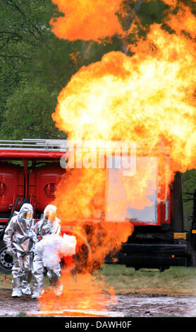 Two firemen in protective suits stand behind a gas fire wall at the gas fire exercise area in Langenhagen, Germany, 24 April 2007. Various technical devices ranging from 12kg hand extinguishers to a special vehicle of Hanover professional fire brigade loaded with 3,000kg of solid extinguishing agent were used in the exercise. Photo: Martin Bosch Stock Photo